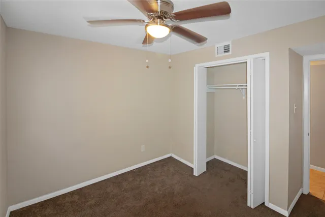 an empty room with closet and a chandelier fan