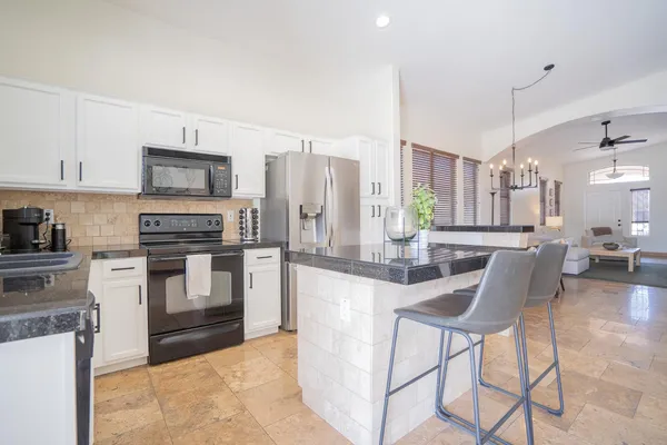 a kitchen with stainless steel appliances granite countertop a stove top oven a sink a dining table and chairs