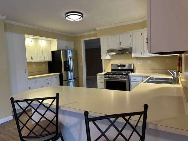 a kitchen with stainless steel appliances a refrigerator a stove a sink a dining table and chairs