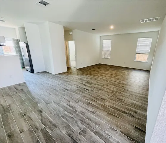 an empty room with wooden floor and windows