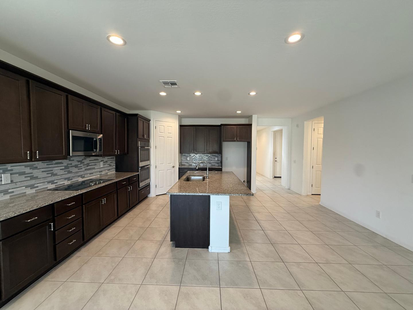 15744 West Jefferson Street Goodyear, AZ 85338 - Photo 13 of 26 a large kitchen with stainless steel appliances granite countertop a large counter top and a stove top oven