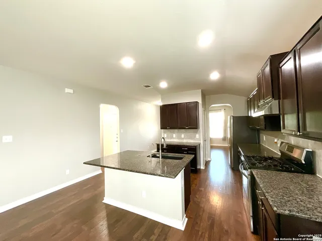a kitchen with stainless steel appliances granite countertop a sink a stove counter space and wooden floor