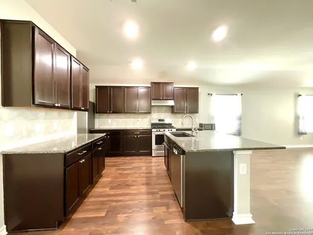 a kitchen with stainless steel appliances granite countertop a stove a sink and a refrigerator