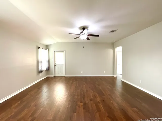 a view of an empty room with a window and wooden floor