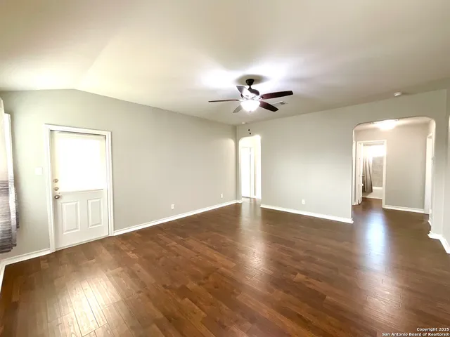 a view of an empty room with a window and wooden floor