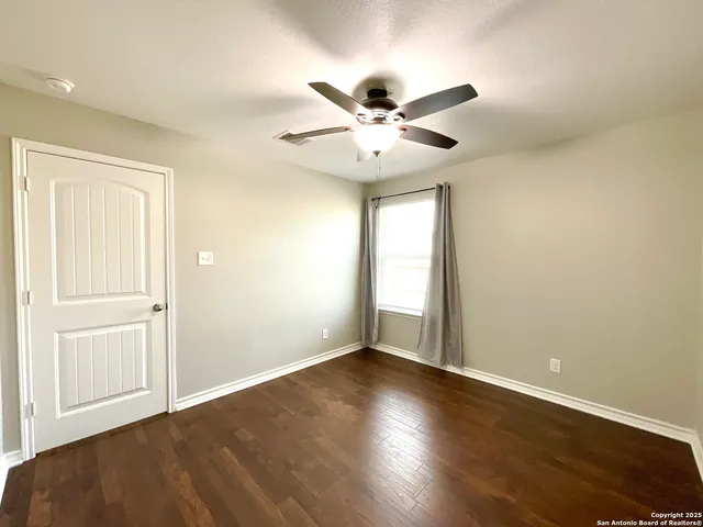 an empty room with wooden floor fan and windows