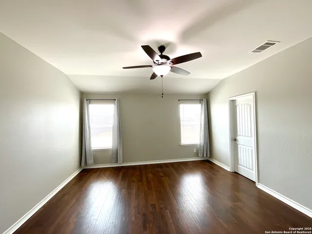 an empty room with wooden floor and windows