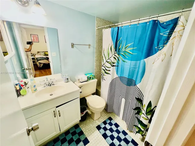 a bathroom with a sink a toilet and shower curtain
