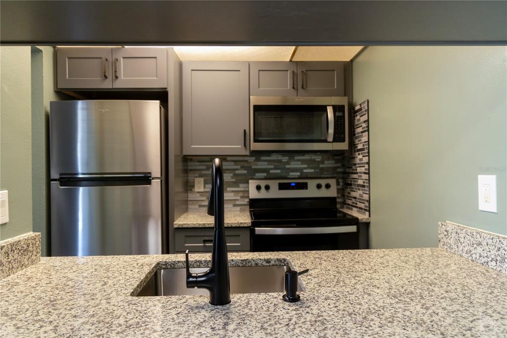 1799 North Highland Avenue, Unit 126 Clearwater, FL 33755 - Photo 6 of 20 a kitchen with stainless steel appliances kitchen island granite countertop a refrigerator stove and microwave