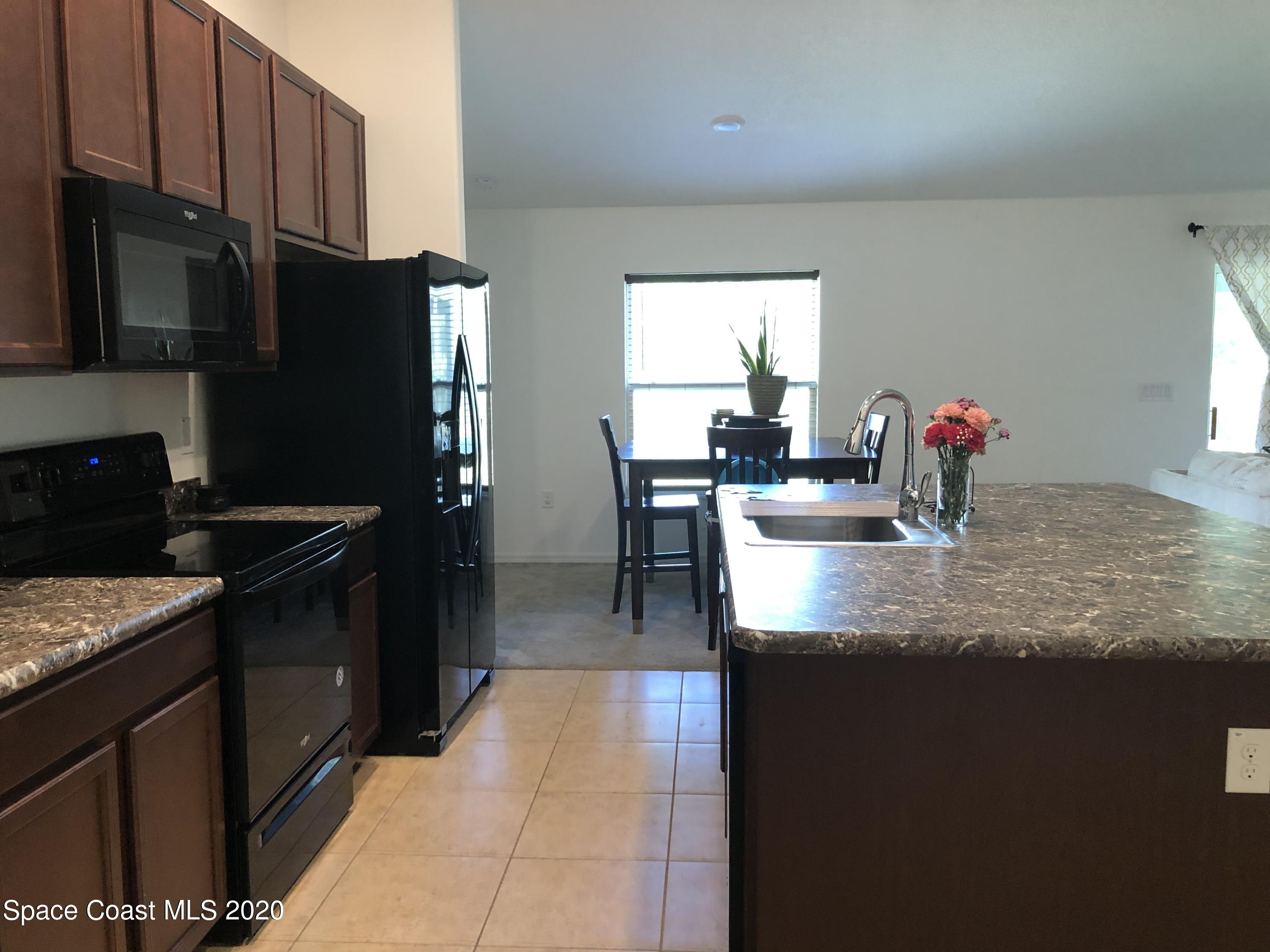 1143 Harlingen Road Southwest, Unit 32 Palm Bay, FL 32908 - Photo 7 of 11 a kitchen with stainless steel appliances granite countertop a sink stove and refrigerator