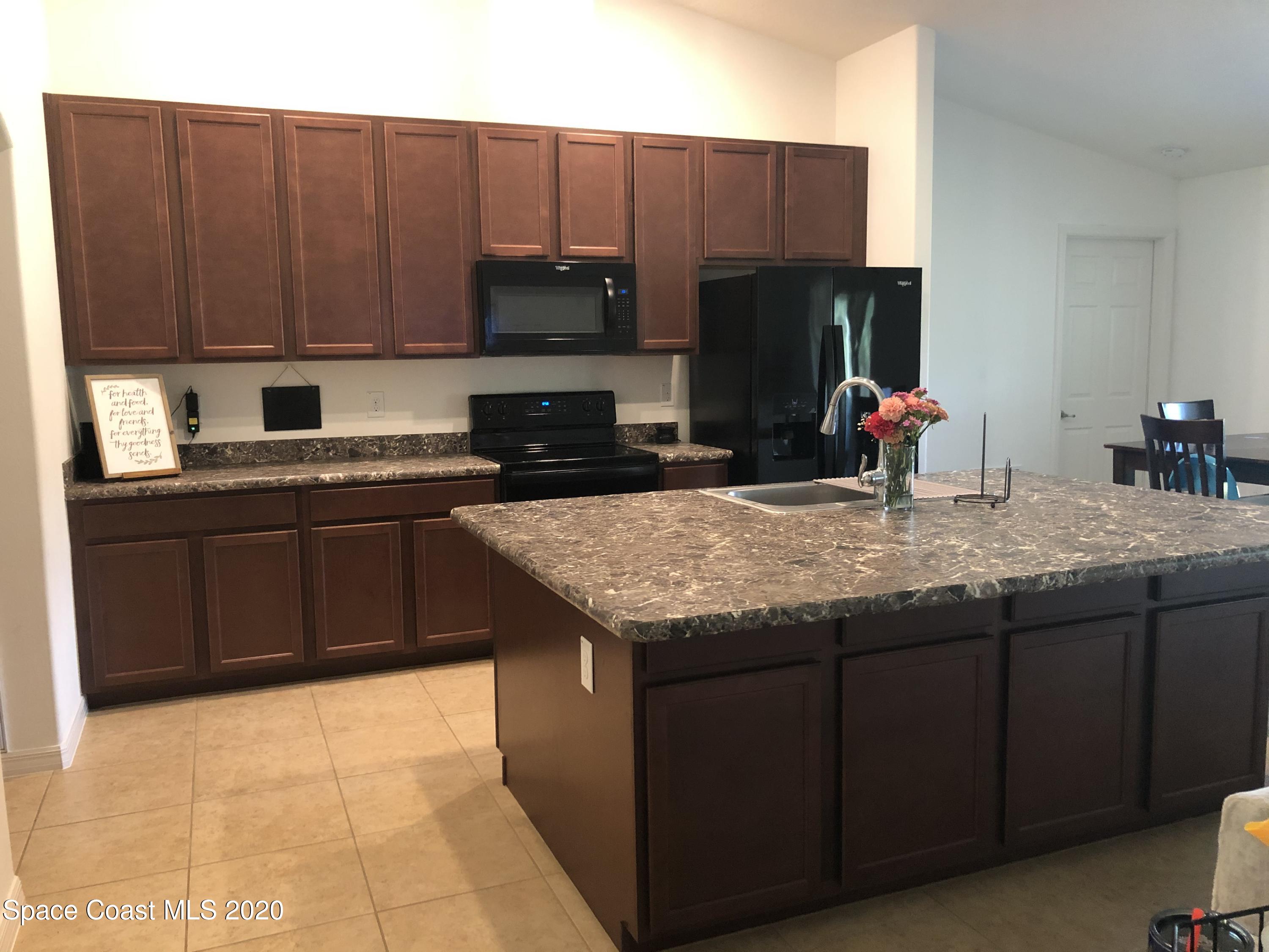 1143 Harlingen Road Southwest, Unit 32 Palm Bay, FL 32908 - Photo 8 of 11 a kitchen with kitchen island granite countertop a sink dishwasher stove and cabinets with wooden floor