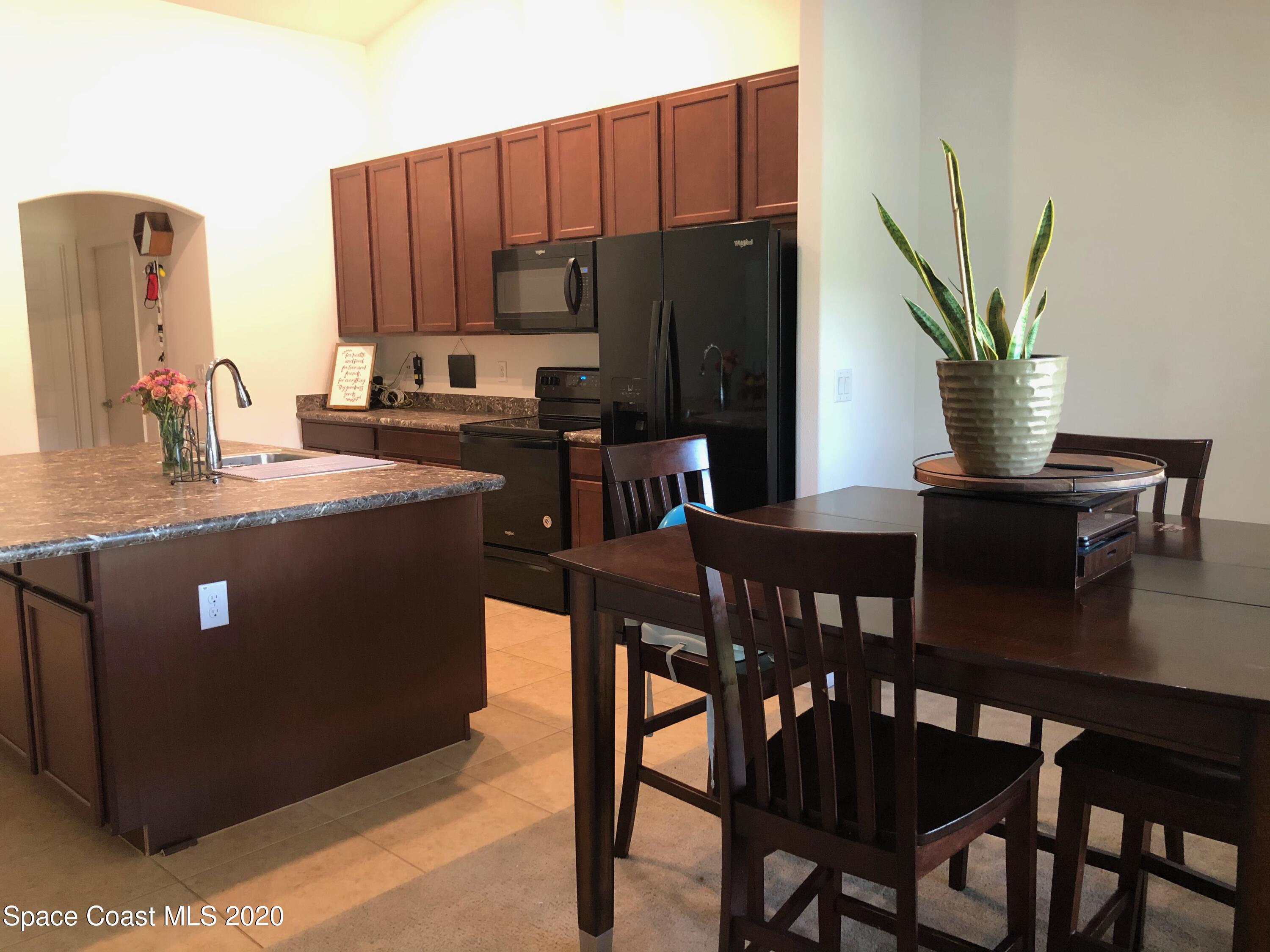 1143 Harlingen Road Southwest, Unit 32 Palm Bay, FL 32908 - Photo 9 of 11 a kitchen with stainless steel appliances a dining table chairs and a refrigerator