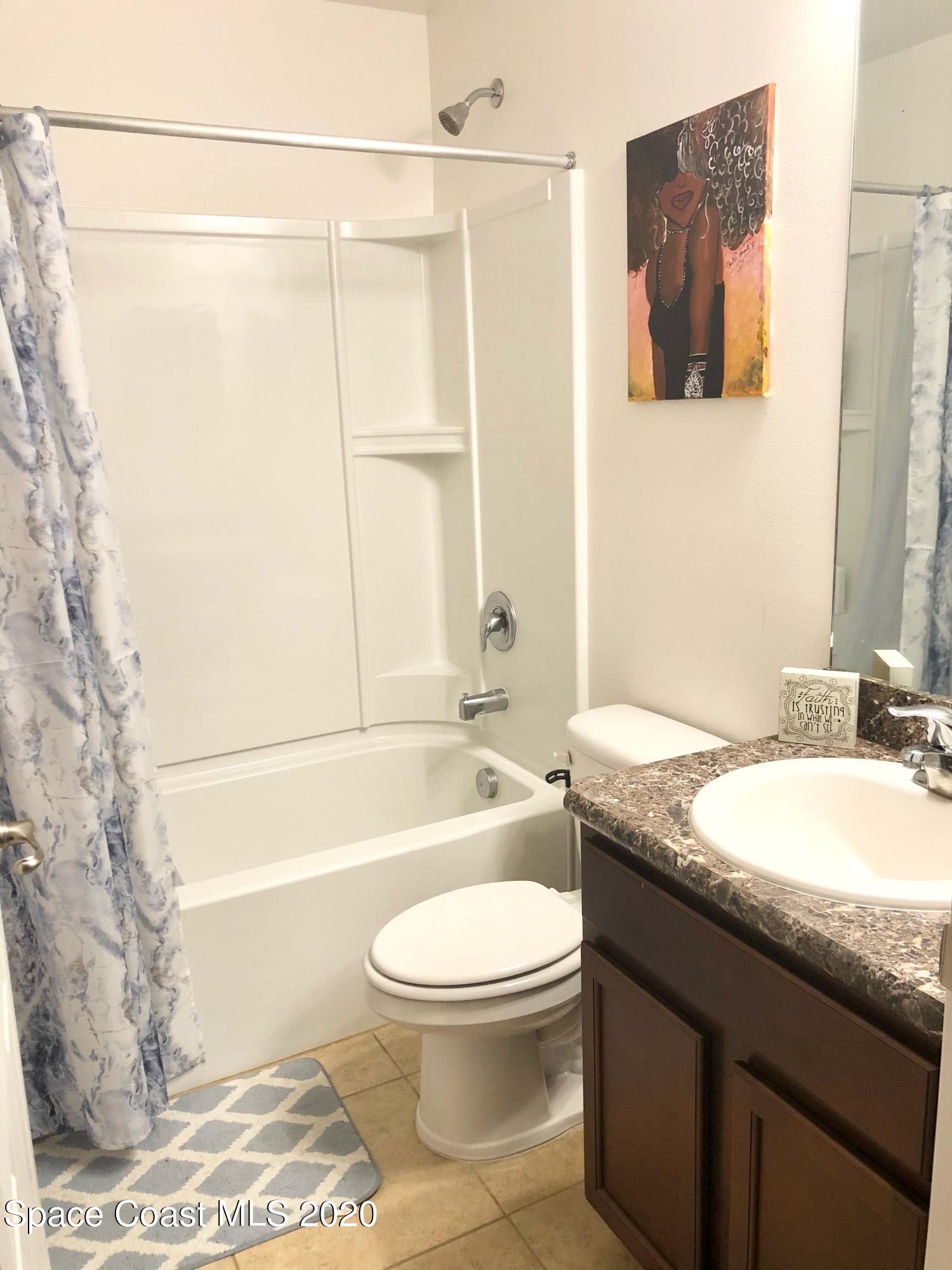 1143 Harlingen Road Southwest, Unit 32 Palm Bay, FL 32908 - Photo 10 of 11 a bathroom with a granite countertop bathtub sink vanity mirror and toilet