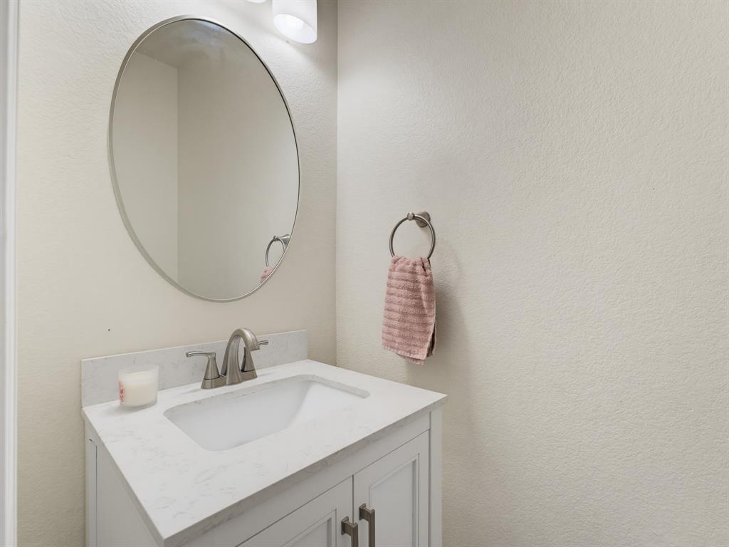 13268 Fencerow Road Fort Worth, TX 76244 - Photo 16 of 25 Modern vanity featuring a white countertop with an integrated sink, brushed nickel faucet, and a wall-mounted oval mirror