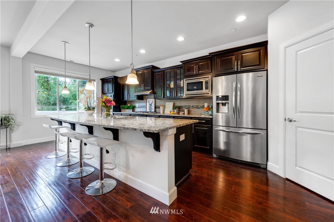 20057 94th Avenue Northeast, Unit 36 Bothell, WA 98011 - Photo 4 of 31 a kitchen with stainless steel appliances a refrigerator a stove a sink dishwasher a dining table and chairs with wooden floor