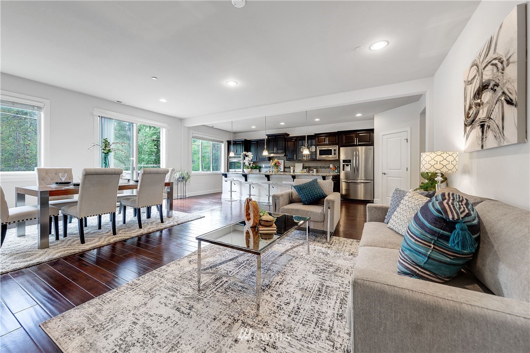 20057 94th Avenue Northeast, Unit 36 Bothell, WA 98011 - Photo 9 of 31 a living room with furniture and a dining table with wooden floor