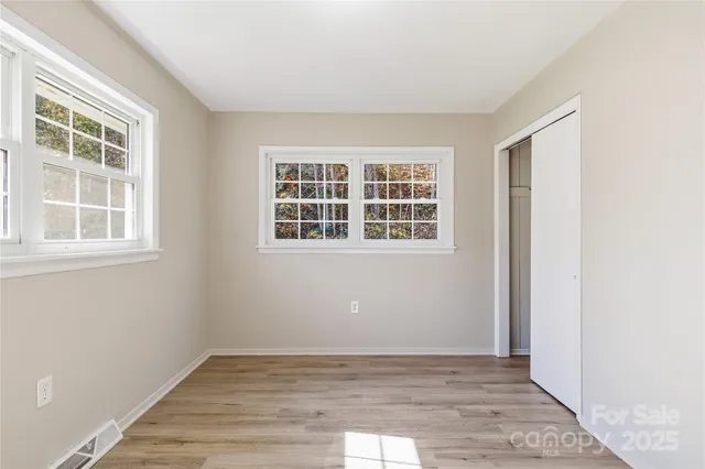 a view of an empty room with wooden floor and windows