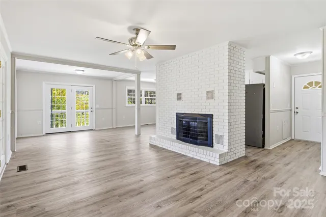 a view of a livingroom with wooden floor a ceiling fan and windows