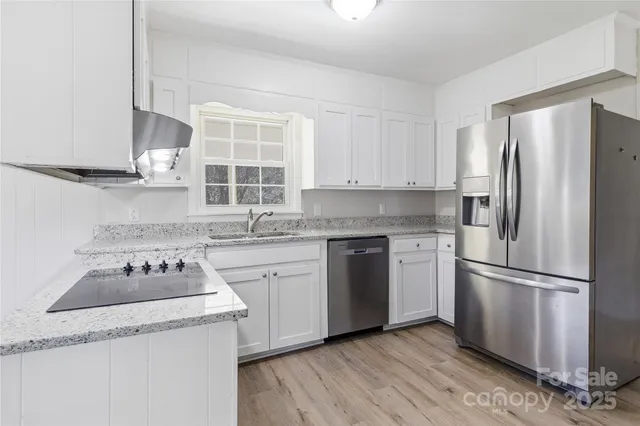 a kitchen with granite countertop stainless steel appliances a refrigerator stove and sink