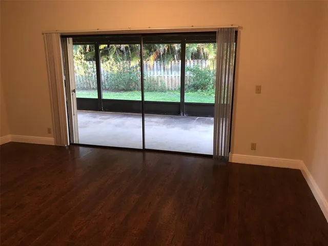 a view of empty room with wooden floor and floor to ceiling window