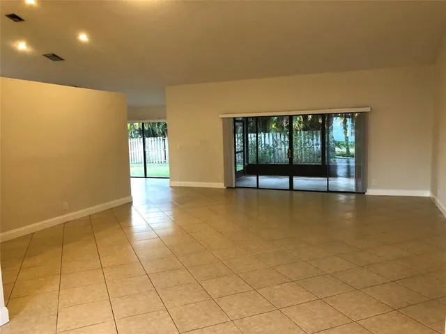 an empty room with floor to ceiling window and ceiling fan