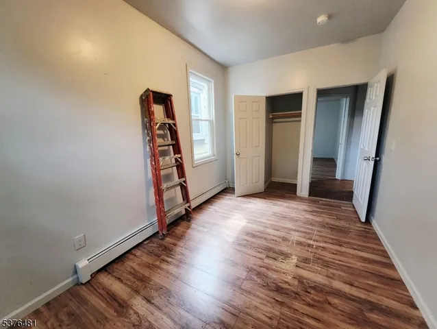 a view of an empty room with wooden floor and stairs