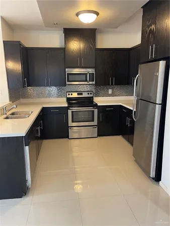 a kitchen with stainless steel appliances a sink a stove a refrigerator and cabinets