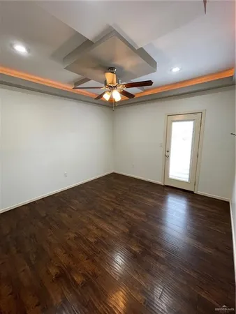 an empty room with wooden floor chandelier fan and windows