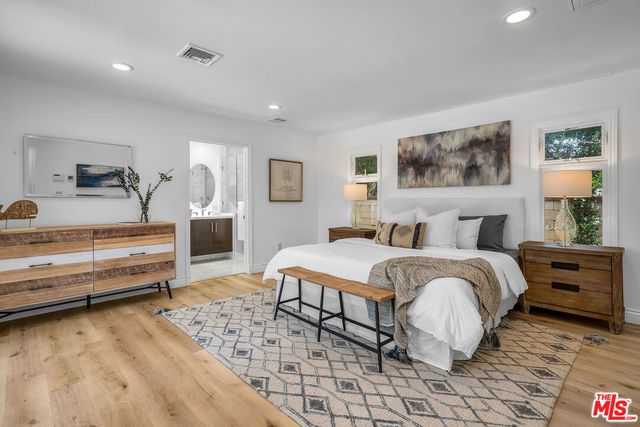 a spacious bedroom with a bed and wooden floor