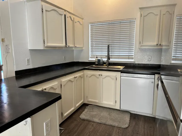a kitchen with granite countertop white cabinets and a sink