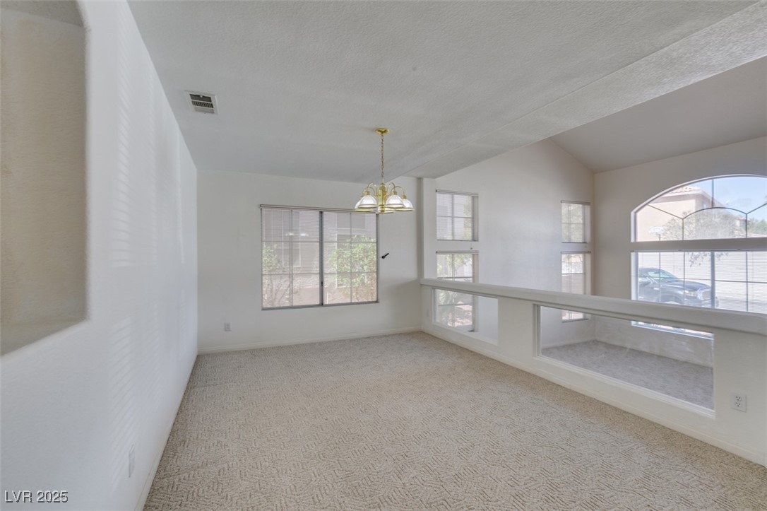 6 High Sierra Henderson, NV 89074 - Photo 13 of 56 Carpeted empty room with a chandelier, vaulted ceiling, a textured ceiling, and baseboards