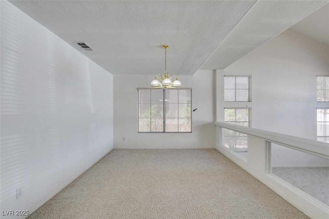 6 High Sierra Henderson, NV 89074 - Photo 14 of 56 Spare room with carpet, a chandelier, a textured ceiling, and baseboards