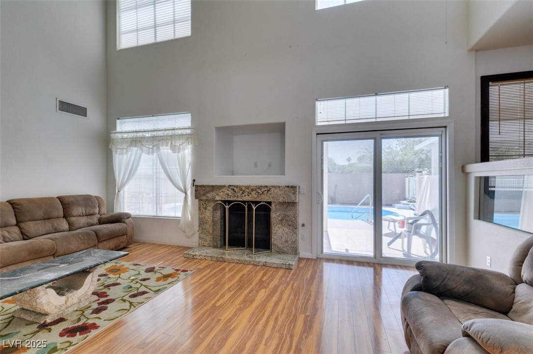 6 High Sierra Henderson, NV 89074 - Photo 18 of 56 Living room featuring a high ceiling, wood finished floors, a high end fireplace, and healthy amount of natural light