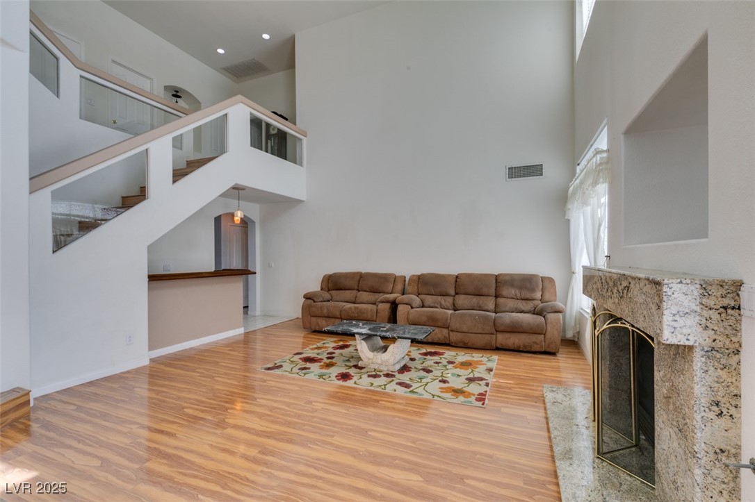 6 High Sierra Henderson, NV 89074 - Photo 20 of 56 Unfurnished living room with light wood-style floors, a towering ceiling, a fireplace, and stairs