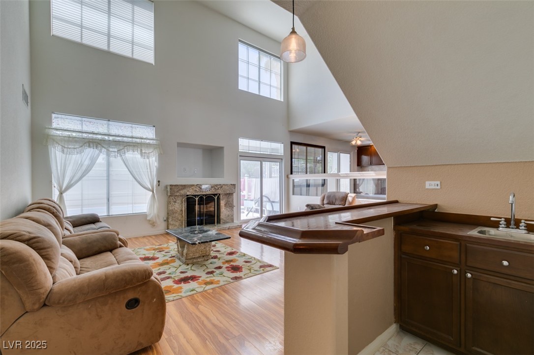 6 High Sierra Henderson, NV 89074 - Photo 22 of 56 Living area featuring a fireplace, a towering ceiling, and light wood-style floors
