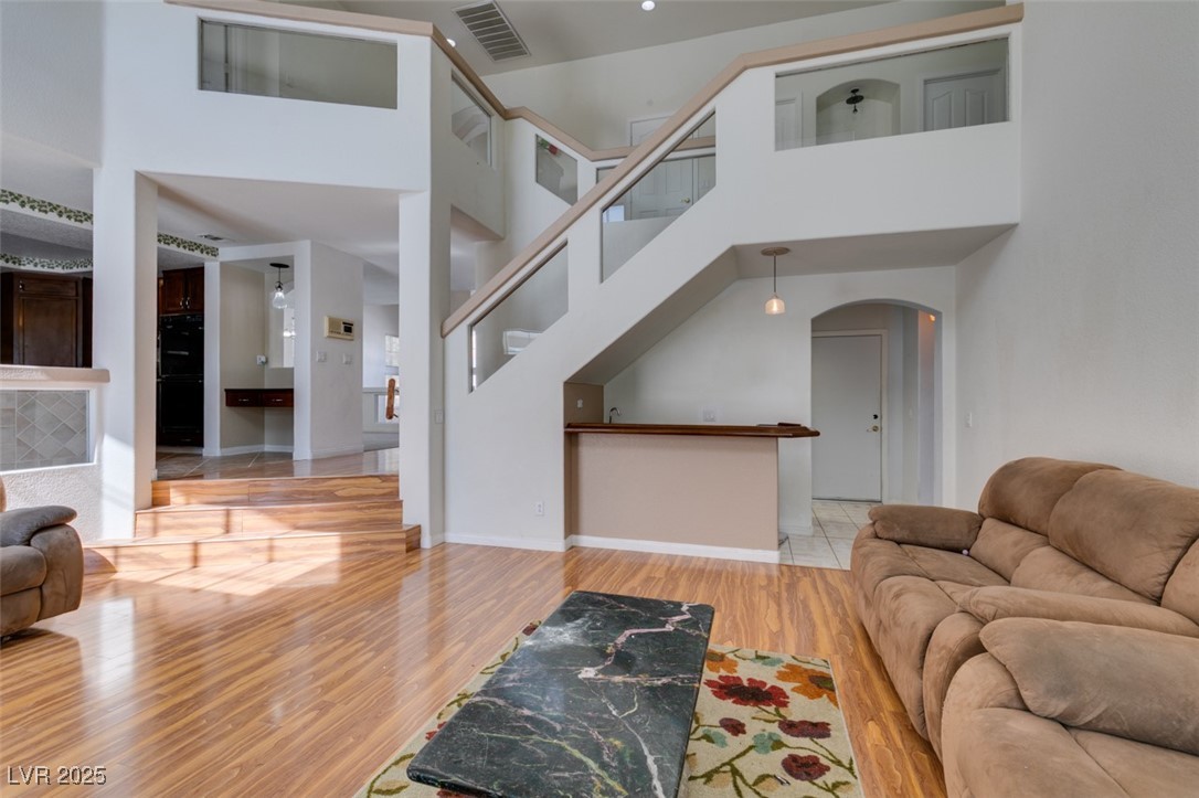 6 High Sierra Henderson, NV 89074 - Photo 26 of 56 Living area with arched walkways, wood finished floors, a towering ceiling, baseboards, and stairway