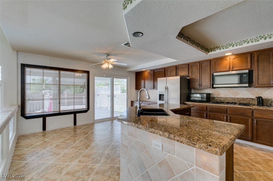 6 High Sierra Henderson, NV 89074 - Photo 27 of 56 Kitchen with a sink, appliances with stainless steel finishes, decorative backsplash, a textured ceiling, and ceiling fan