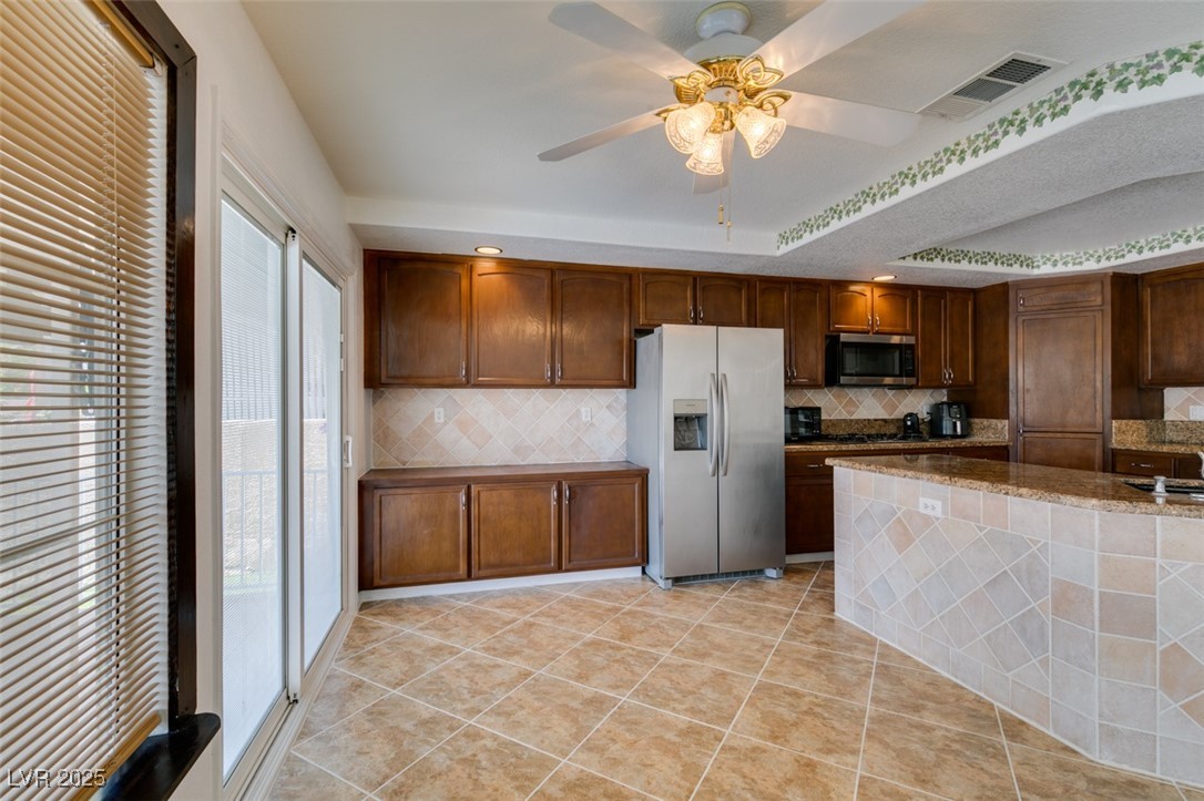 6 High Sierra Henderson, NV 89074 - Photo 30 of 56 Kitchen featuring appliances with stainless steel finishes, decorative backsplash, dark stone counters, and ceiling fan