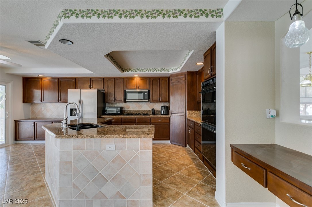 6 High Sierra Henderson, NV 89074 - Photo 35 of 56 Kitchen featuring stainless steel appliances, a raised ceiling, a sink, plenty of natural light, and a textured ceiling