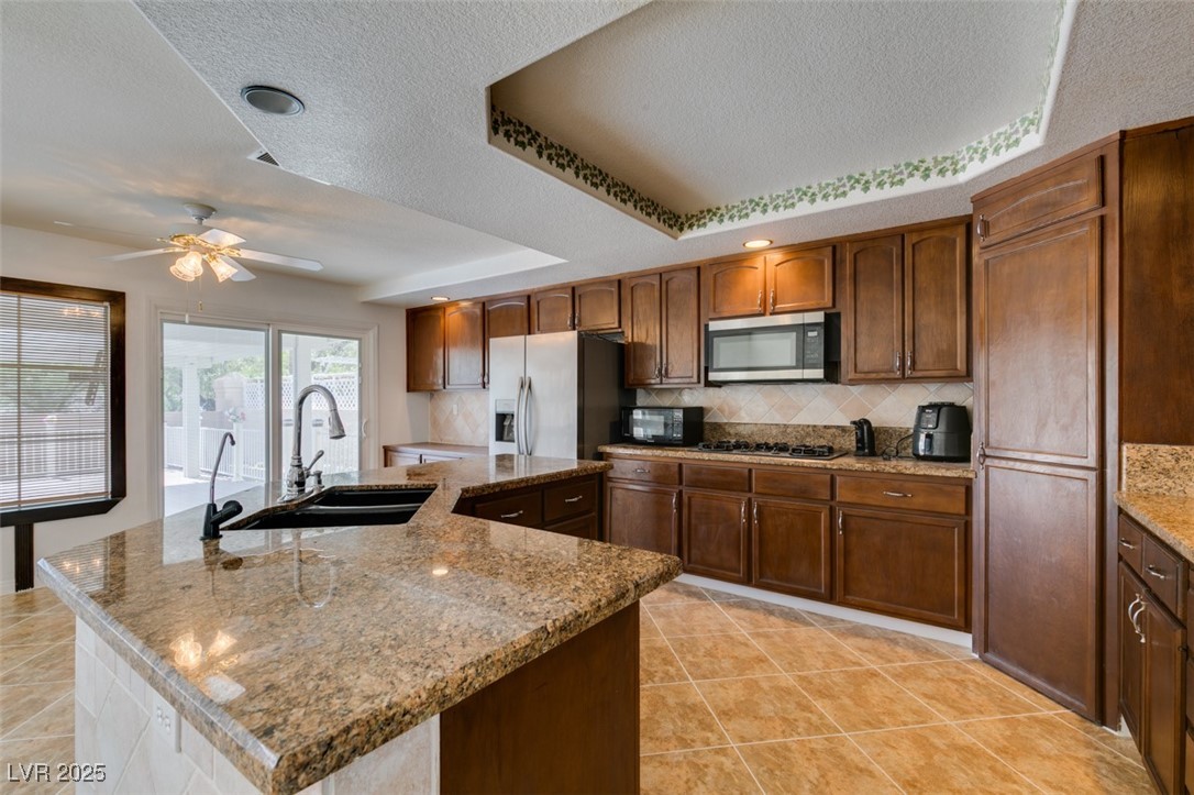 6 High Sierra Henderson, NV 89074 - Photo 36 of 56 Kitchen featuring stainless steel microwave, a sink, refrigerator with ice dispenser, gas stovetop, and a ceiling fan
