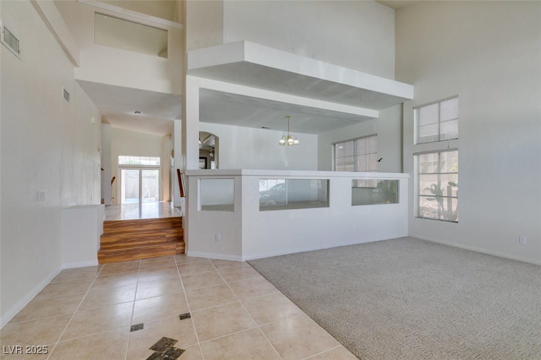 6 High Sierra Henderson, NV 89074 - Photo 4 of 56 Unfurnished living room with a high ceiling, a chandelier, tile patterned flooring, and baseboards
