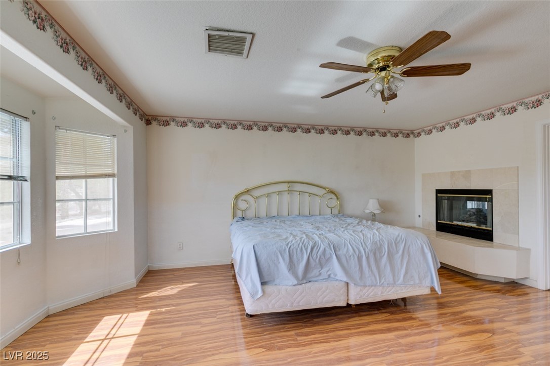 6 High Sierra Henderson, NV 89074 - Photo 44 of 56 Bedroom with light wood-style flooring, baseboards, a glass covered fireplace, and a ceiling fan