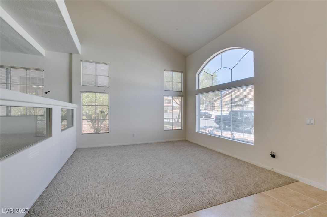 6 High Sierra Henderson, NV 89074 - Photo 6 of 56 Carpeted spare room featuring high vaulted ceiling, baseboards, and tile patterned flooring