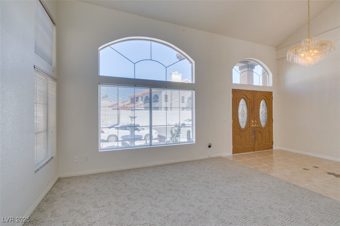 6 High Sierra Henderson, NV 89074 - Photo 8 of 56 Carpeted foyer entrance featuring high vaulted ceiling, a chandelier, plenty of natural light, tile patterned floors, and baseboards