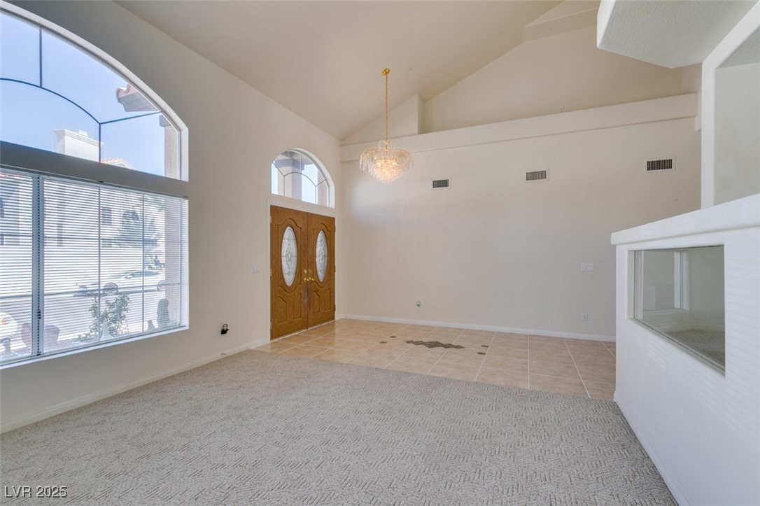 6 High Sierra Henderson, NV 89074 - Photo 9 of 56 Carpeted foyer entrance featuring a chandelier, healthy amount of natural light, high vaulted ceiling, and tile patterned floors