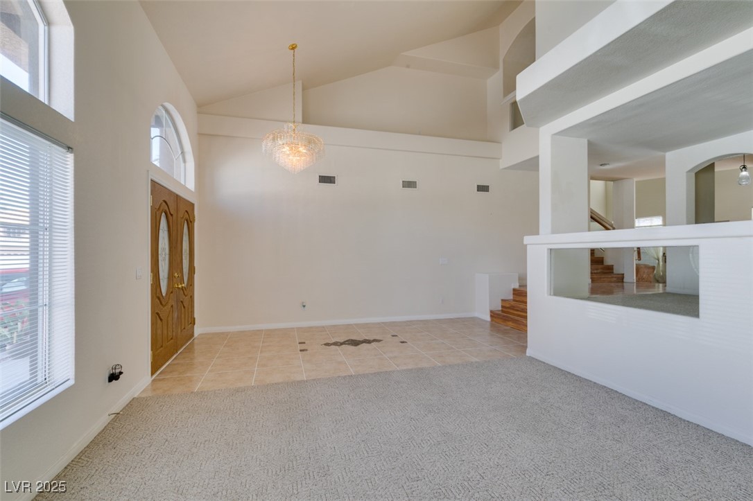 6 High Sierra Henderson, NV 89074 - Photo 10 of 56 Unfurnished room with carpet floors, tile patterned flooring, high vaulted ceiling, and stairs
