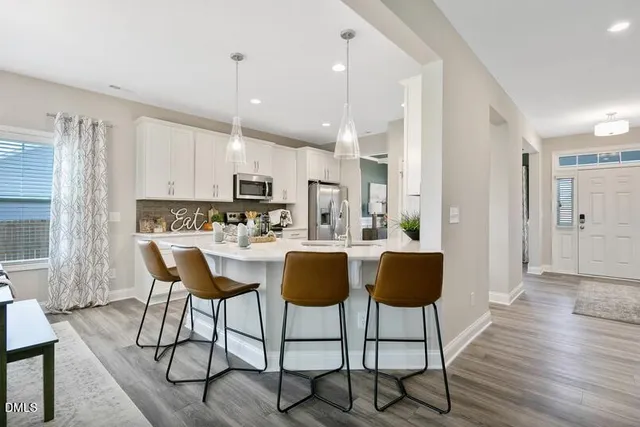 a kitchen with stainless steel appliances granite countertop a dining table chairs and view living room
