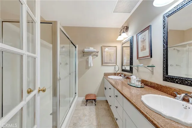 a spacious bathroom with a double vanity sink a mirror and a shower