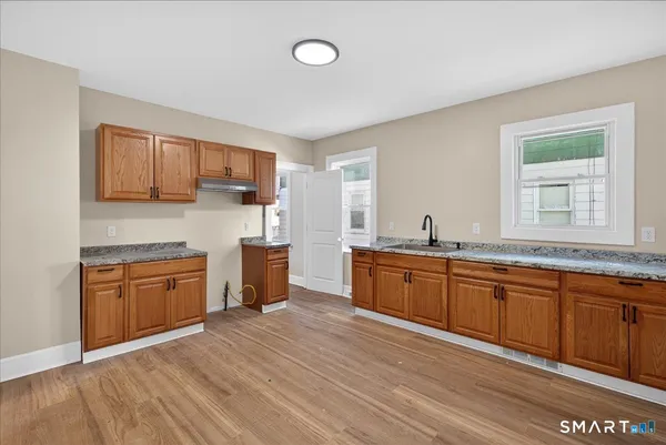 a large kitchen with stainless steel appliances granite countertop a sink dishwasher stove and wooden cabinets