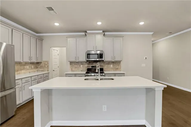 a kitchen with kitchen island a counter space a sink appliances and cabinets